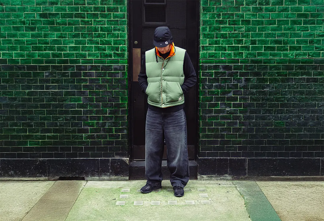 man wearing baggy jeans with new balance shoes, stussy gilet and longsleeve