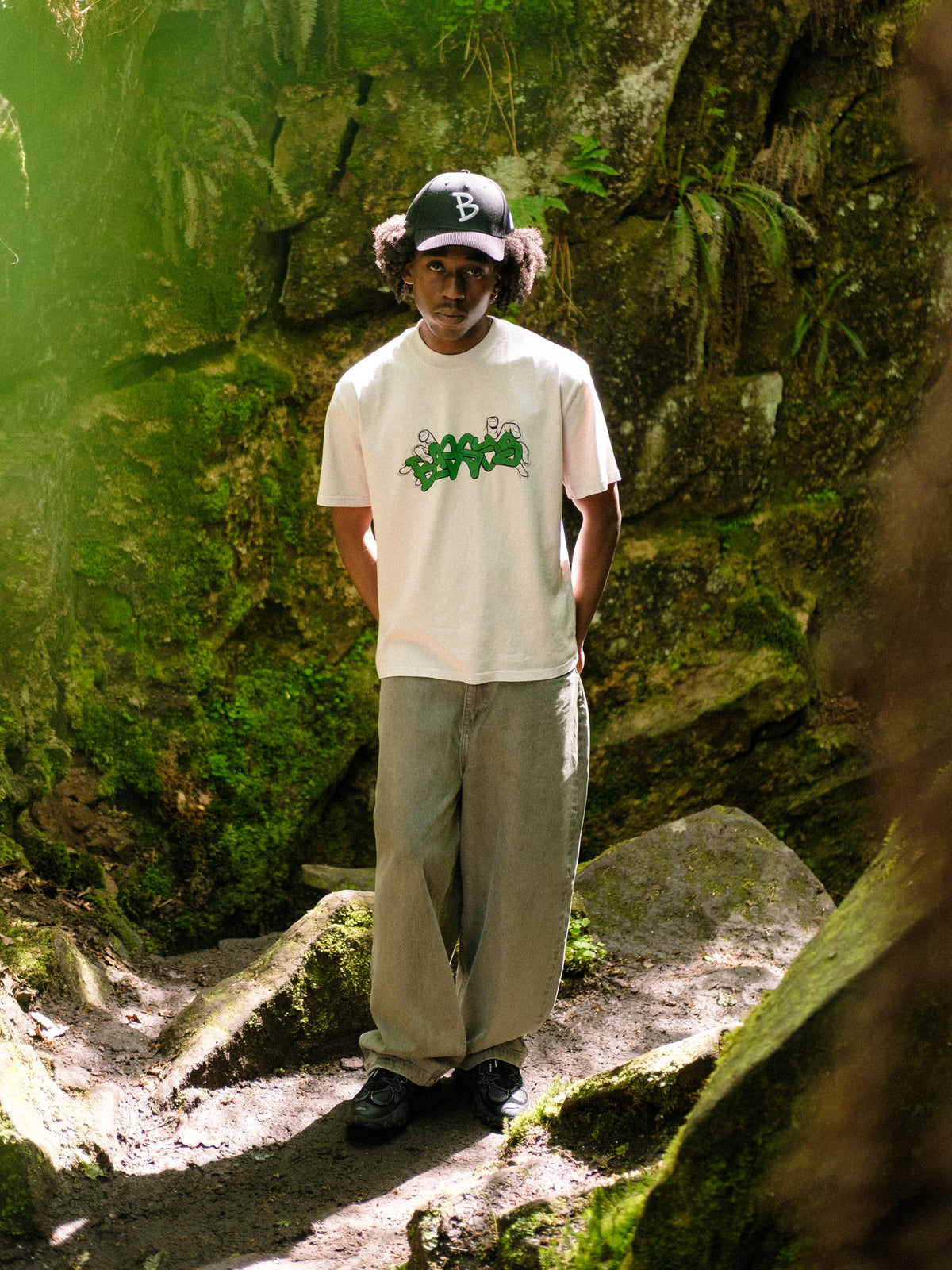 Model in woodland, wearing baggys hat, grab t-shirt and denim pant sage