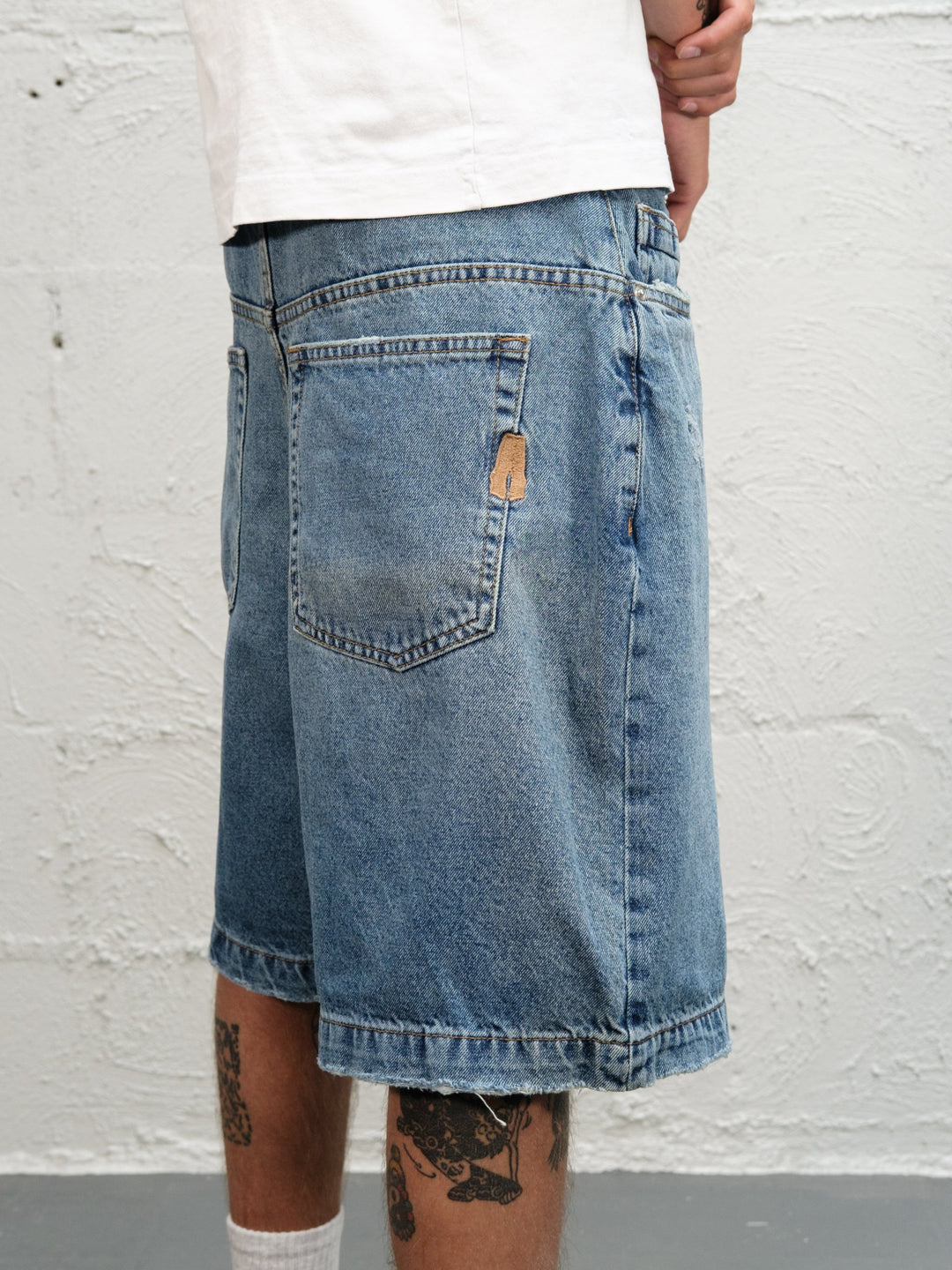 Model wearin Denim Short | Fray paired with 95's and a white t-shirt close up rear