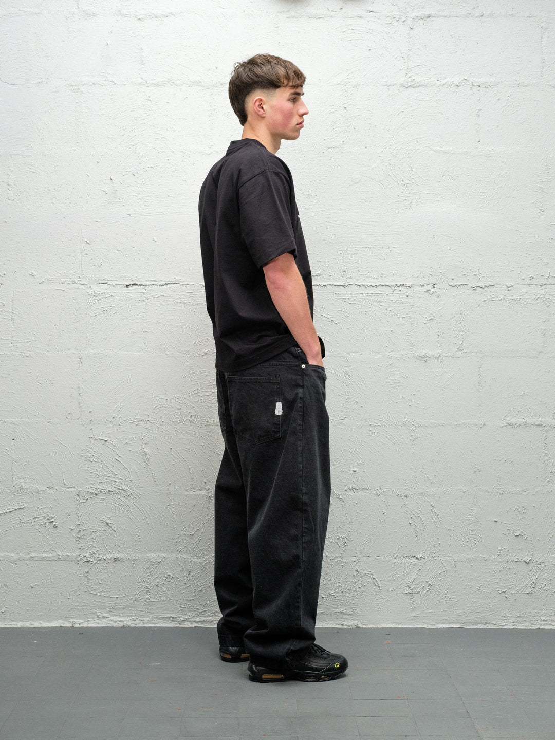 Person wearing black baggy denim pitch jeans, made by Baggys.uk