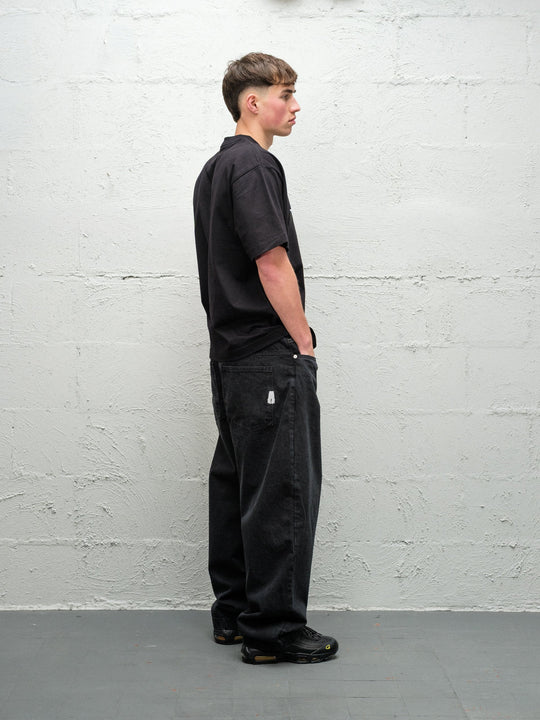 Person wearing black baggy denim pitch jeans, made by Baggys.uk