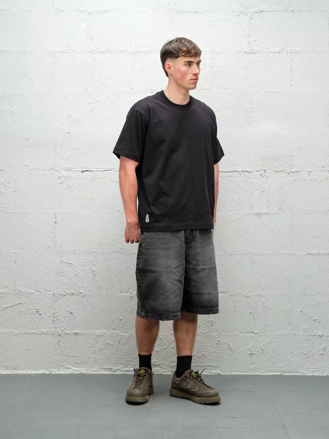 Person wearing black baggy denim fade jean shorts, made by Baggys.uk