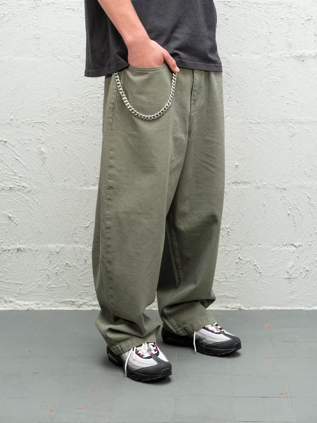Person wearing Sage green baggy denim pants with the wallet chain