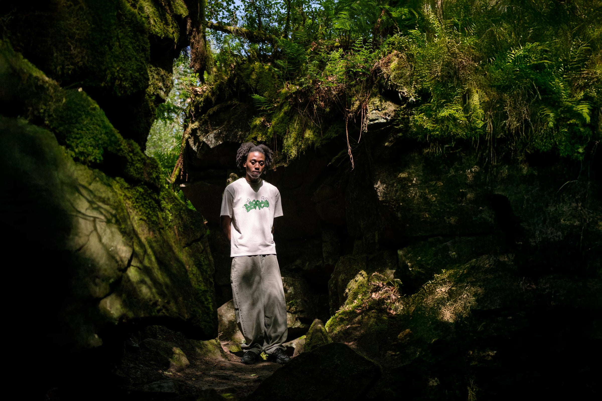 Model in woodland area, wearing grab t-shirt in bone and denim pant sage