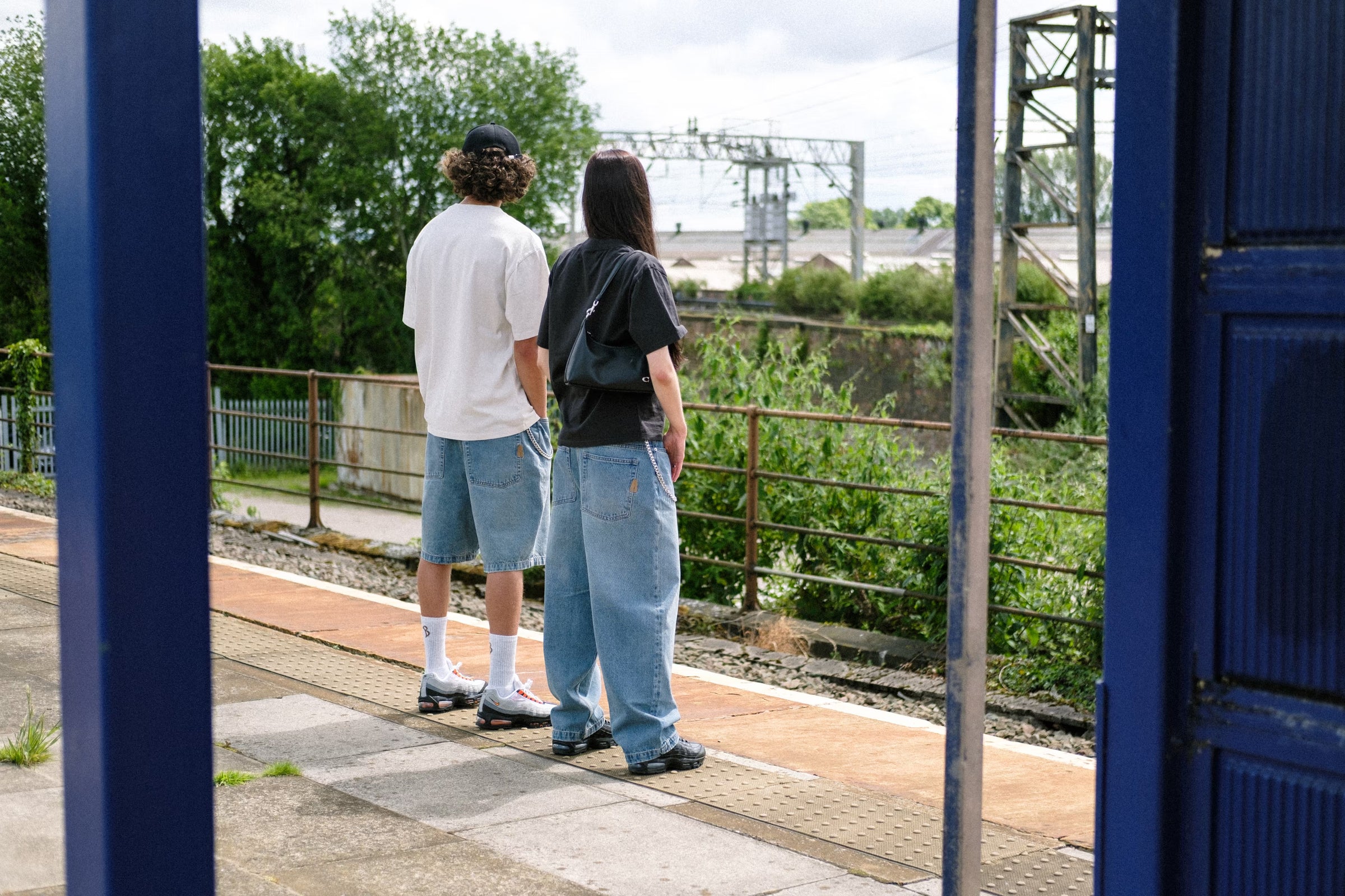 Two models are the train station, wearing denim pant fray and denim short fray