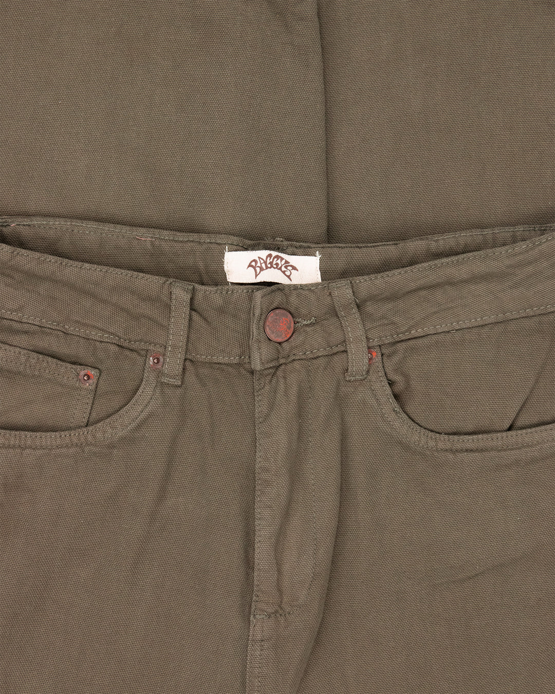 Close-up of brown pants with a brand label on the waistband.