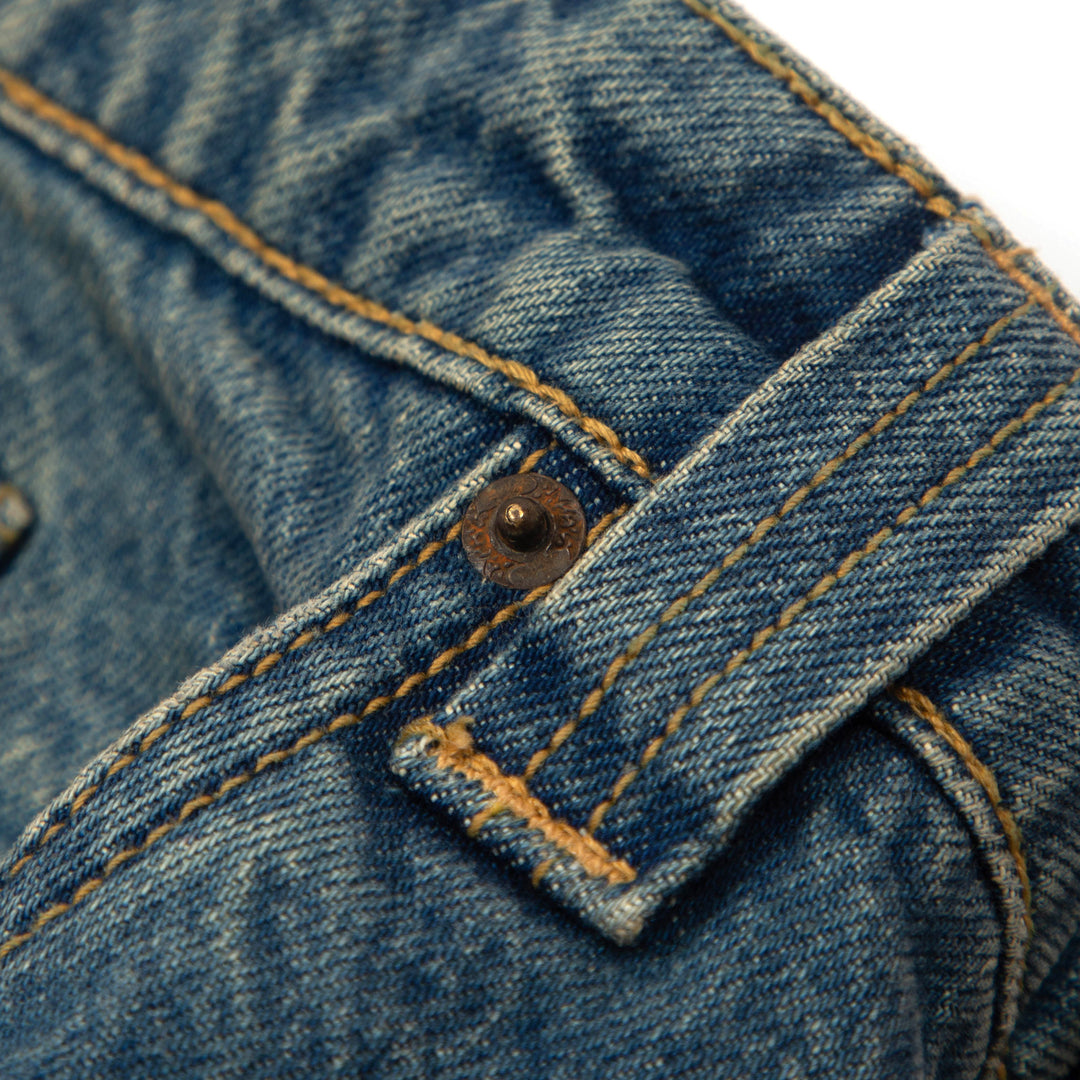 the Baggy Blues custom logo rivets in a rust metal colour, with the yellow tonal chain stitching