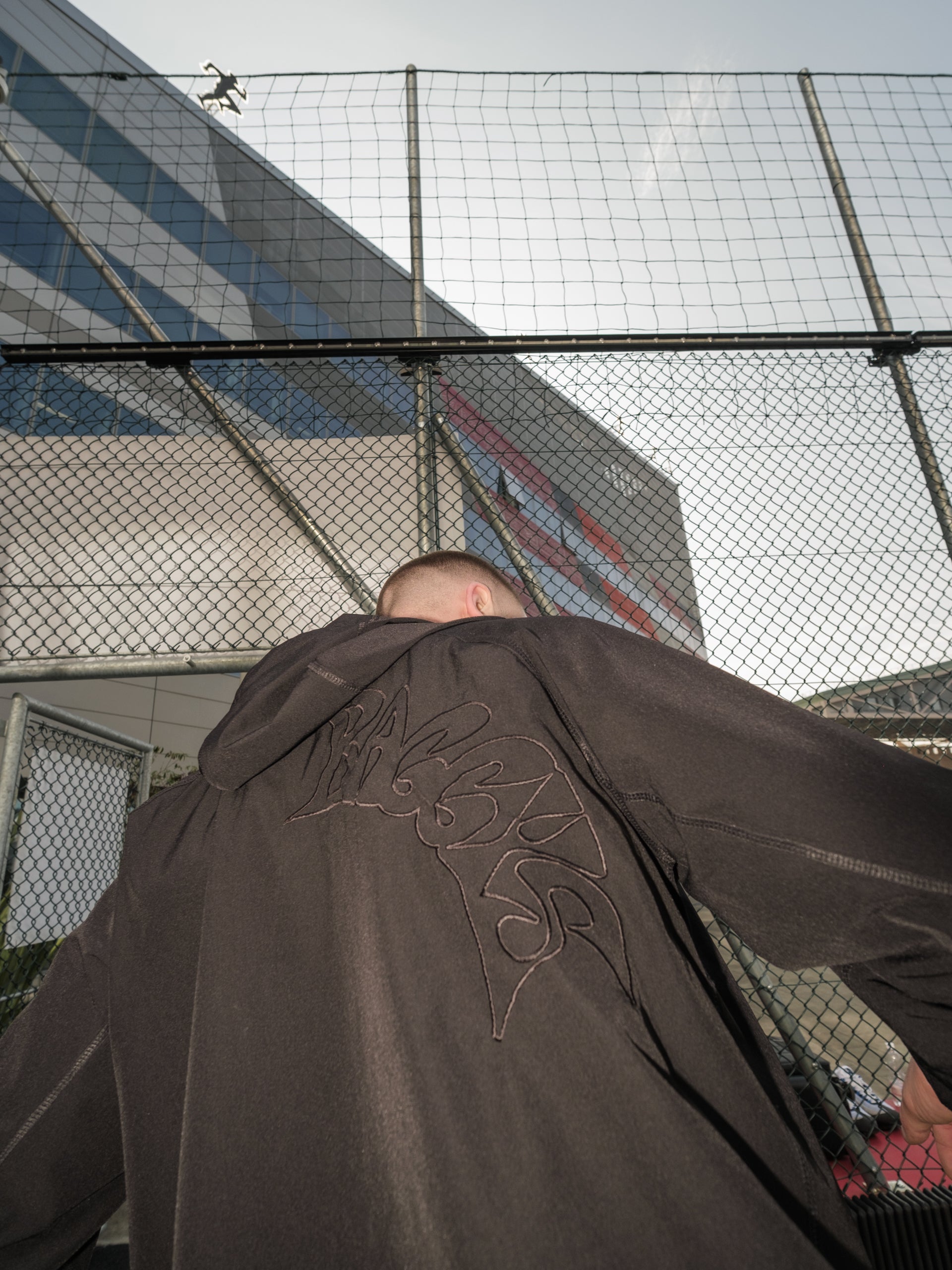 Person wearing Baggy Vanta Black Track Jacket showing embroidery in Milan
