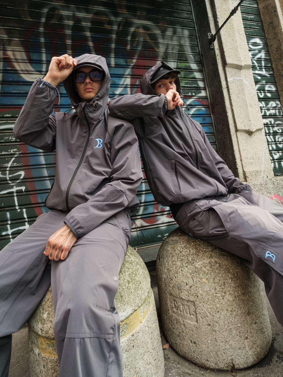 two men wearing baggys vanta tracksuit in milan with graffiti background 