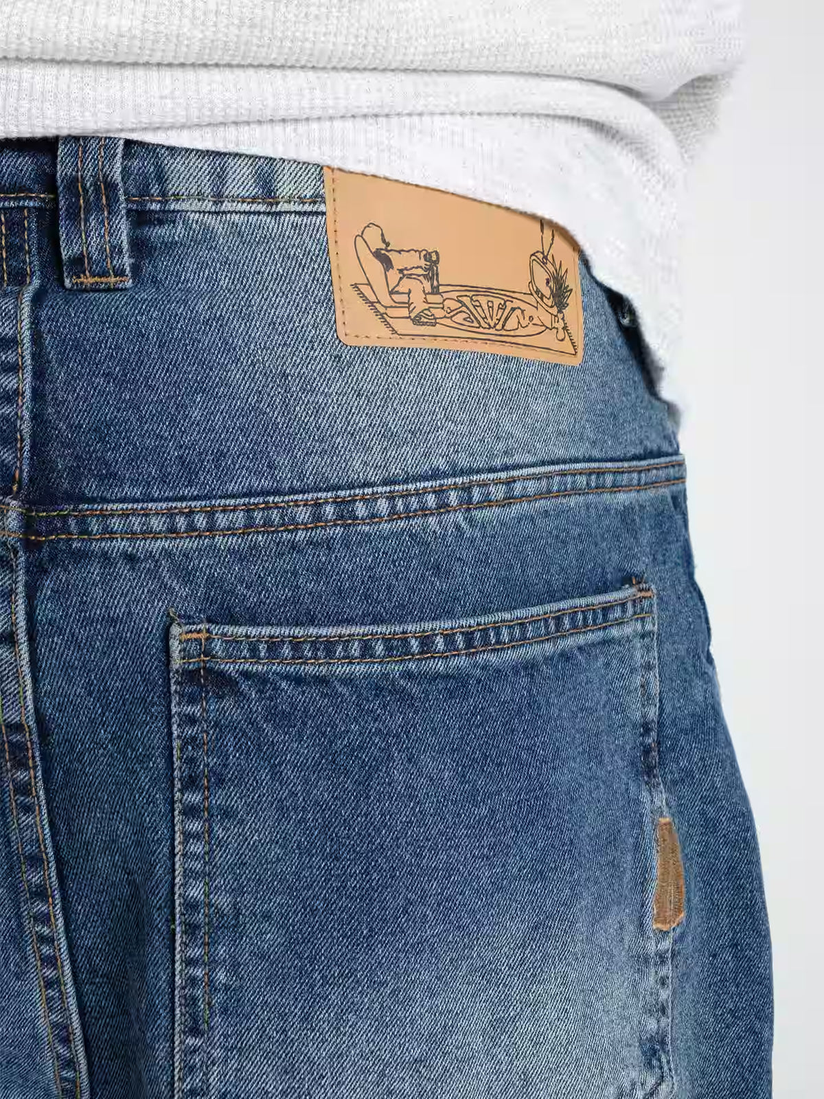 Person wearing Baggy Jeans Frost blue, showing the close up detailing of the belt patch and wash