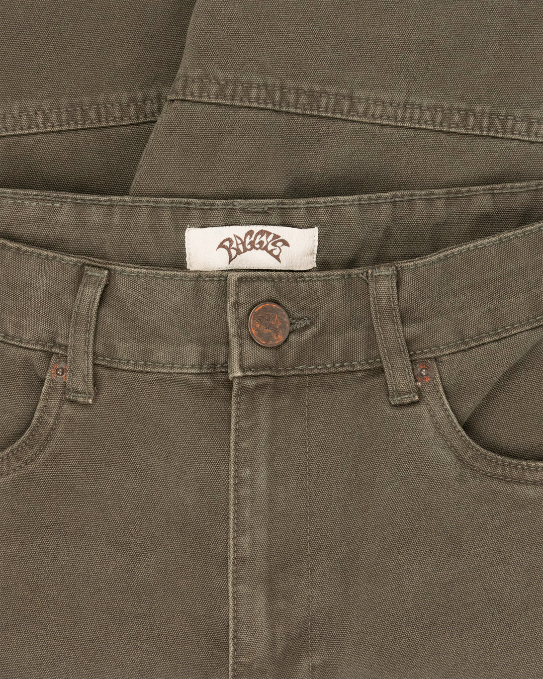 Close-up of a brown pants waistband with a brand label and button.