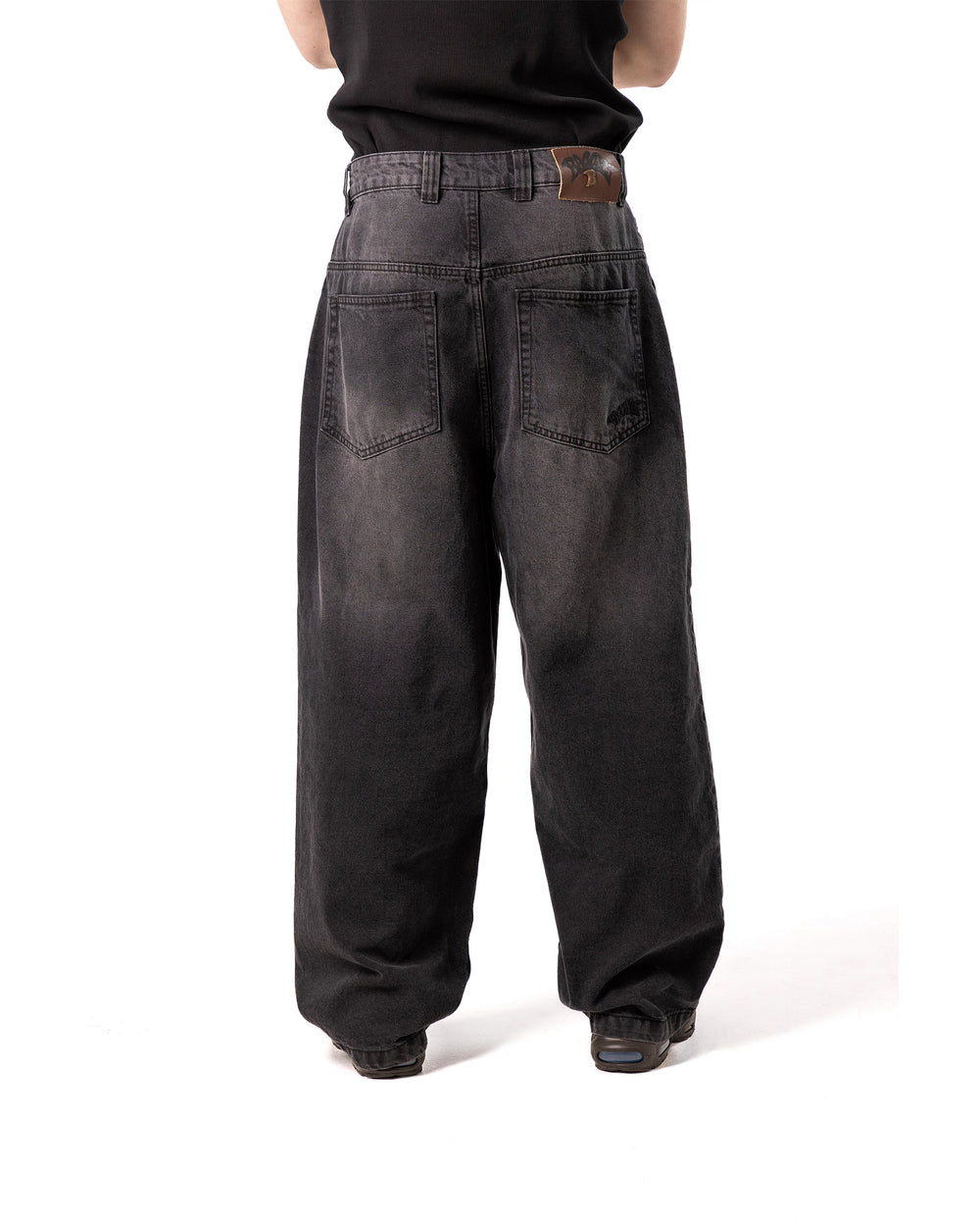 Person wearing black wide-leg jeans on a white background
