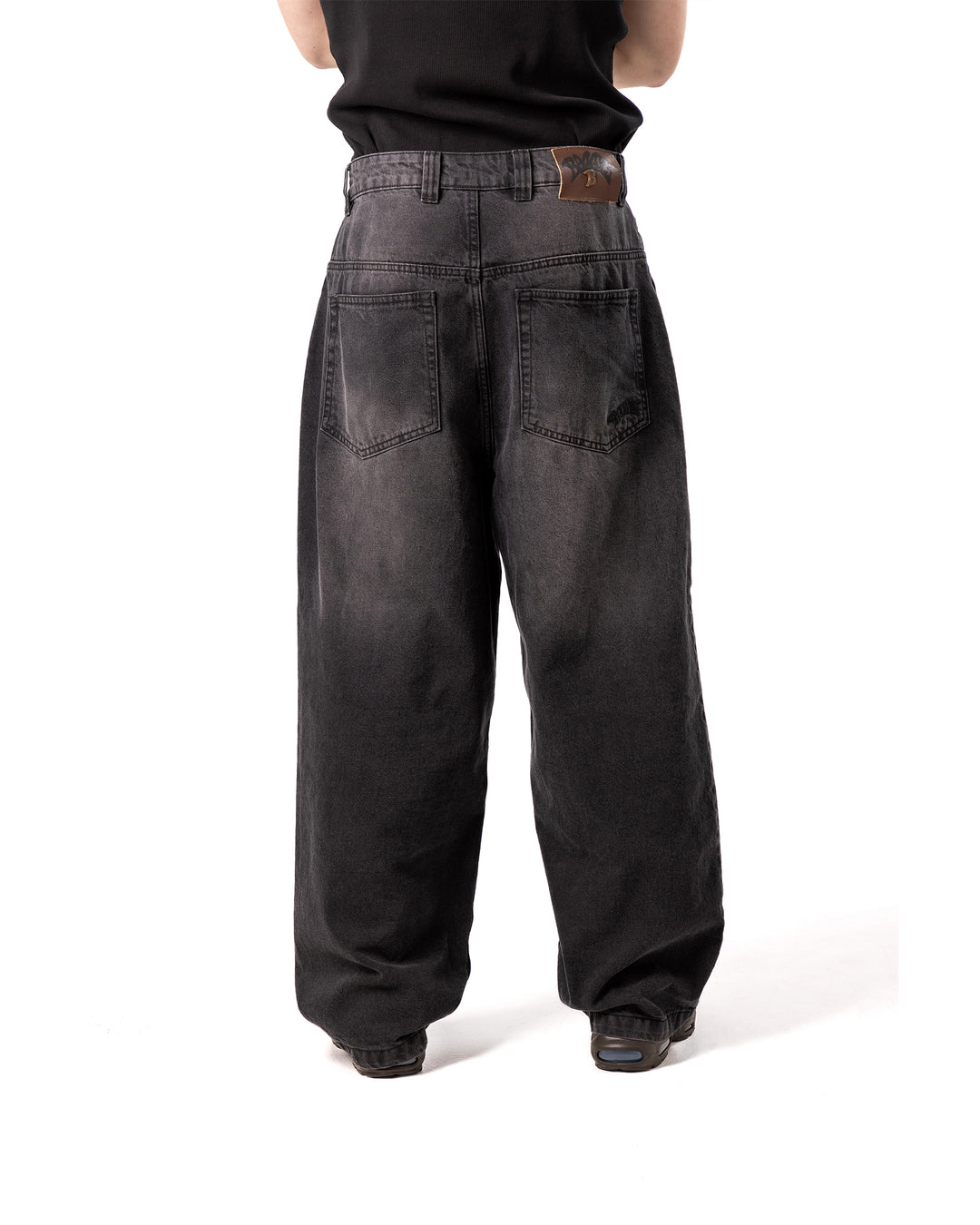 Person wearing black wide-leg jeans on a white background